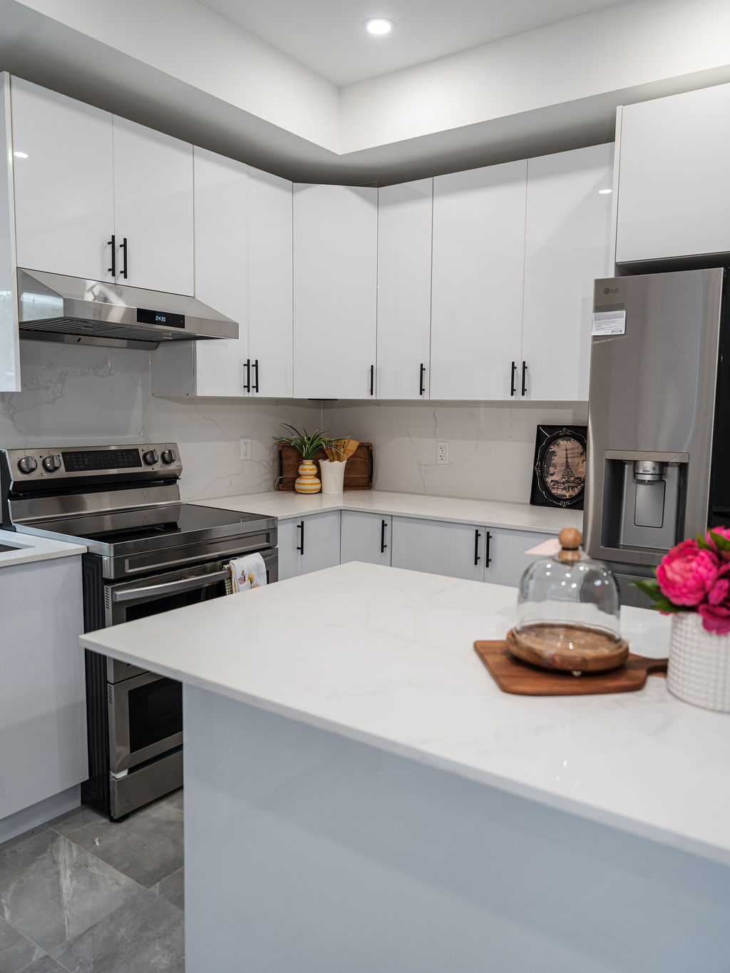Modern all-white flat-panel European style kitchen with minimalist handleless cabinets in a bright showroom setting