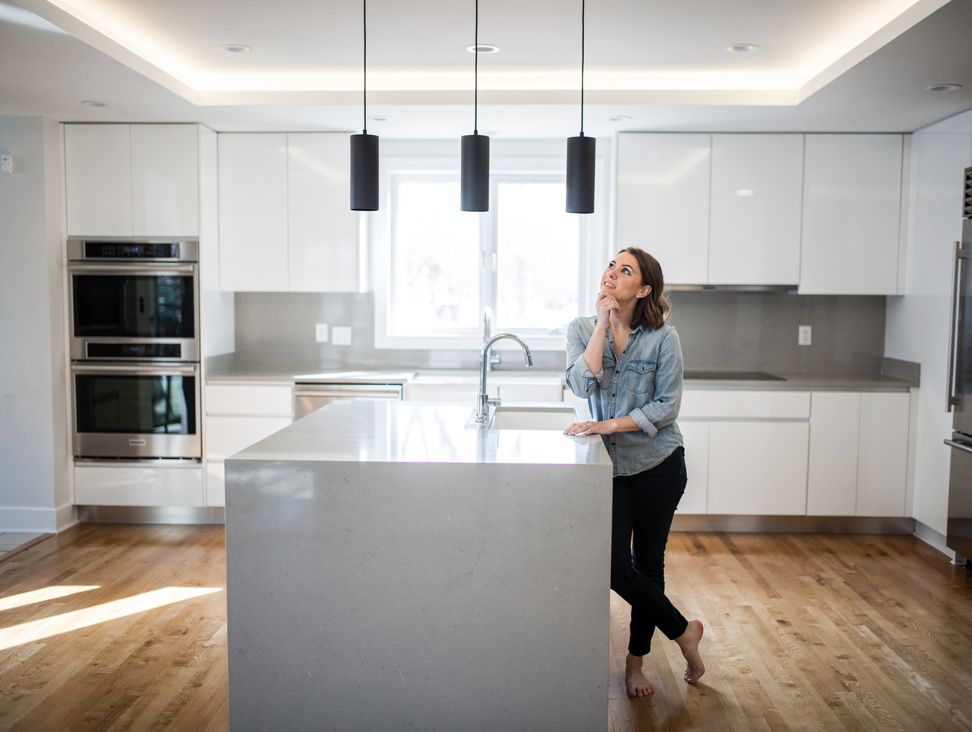 Bright modern kitchen showroom with island, quartz countertops, and clean cabinetry